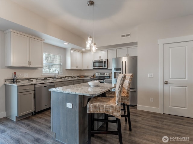 kitchen featuring visible vents, dark wood finished floors, a breakfast bar area, appliances with stainless steel finishes, and a sink