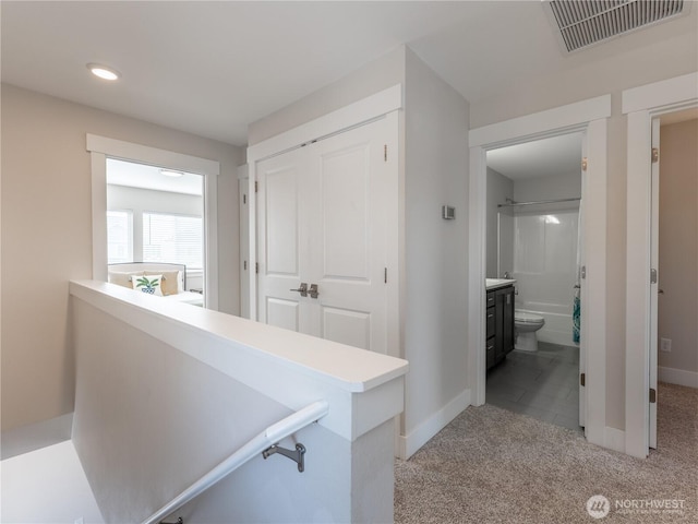 hallway featuring recessed lighting, visible vents, light colored carpet, and baseboards