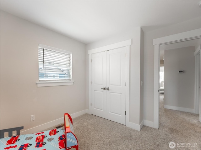 carpeted bedroom featuring baseboards and a closet