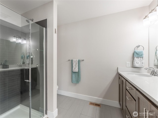 bathroom with visible vents, baseboards, toilet, a stall shower, and vanity