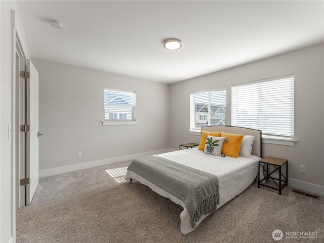 carpeted bedroom with visible vents, multiple windows, and baseboards