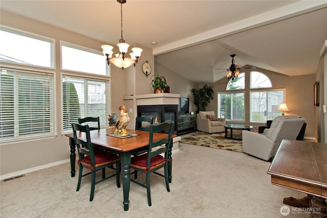 dining area with visible vents, ceiling fan with notable chandelier, lofted ceiling with beams, carpet, and a multi sided fireplace