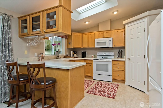 kitchen featuring white appliances, a peninsula, a sink, light countertops, and glass insert cabinets