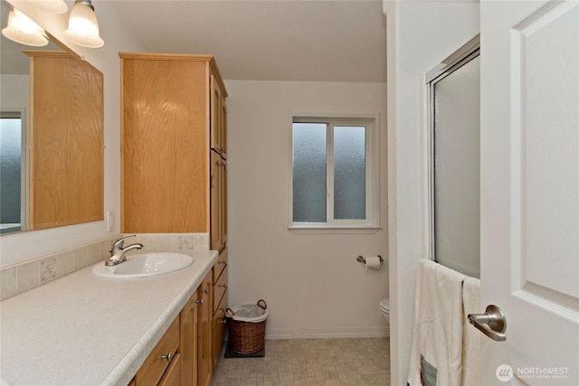 bathroom featuring a shower with shower door, tile patterned floors, toilet, baseboards, and vanity