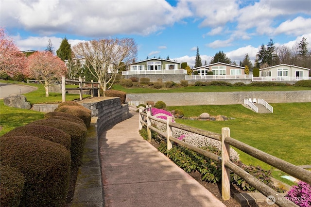 view of community featuring a lawn and fence