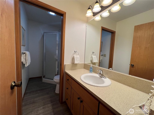 full bathroom featuring vanity, wood finished floors, a stall shower, a notable chandelier, and toilet