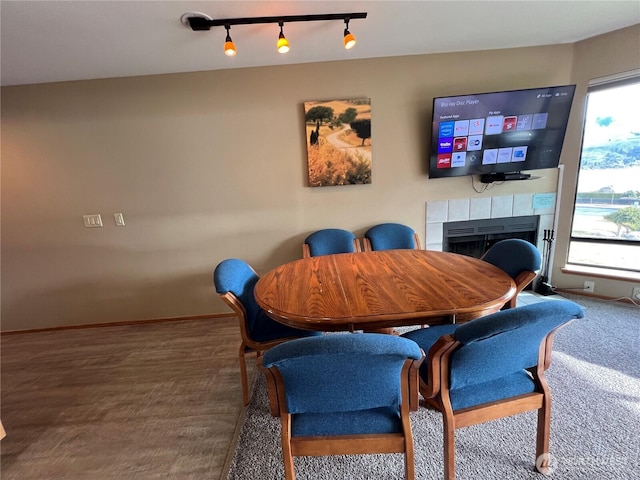 dining area with a tiled fireplace, plenty of natural light, track lighting, and baseboards