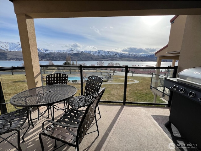 balcony featuring outdoor dining space and a water and mountain view