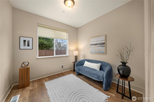 living area featuring visible vents, baseboards, and wood finished floors