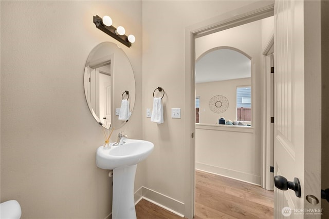 half bath with baseboards and wood finished floors