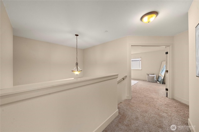 corridor with an upstairs landing, light colored carpet, and baseboards