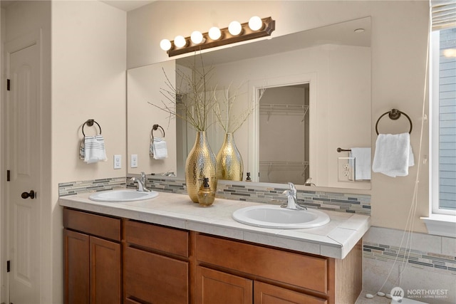 full bath with double vanity, tasteful backsplash, and a sink