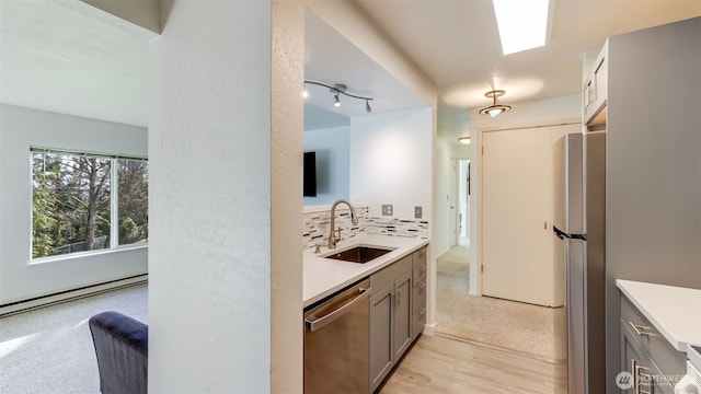 kitchen with a sink, light countertops, stainless steel appliances, and gray cabinetry