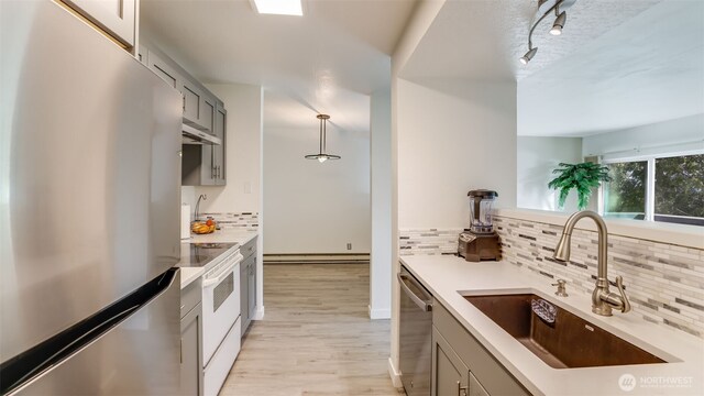 kitchen featuring a sink, light countertops, gray cabinets, stainless steel appliances, and a baseboard radiator