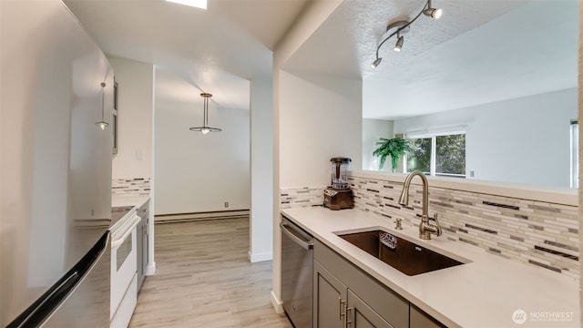 kitchen featuring gray cabinetry, a sink, light countertops, stainless steel dishwasher, and light wood-type flooring