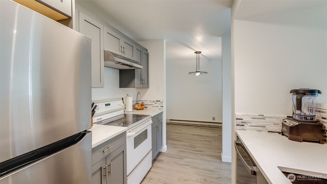 kitchen with backsplash, under cabinet range hood, baseboard heating, gray cabinets, and appliances with stainless steel finishes