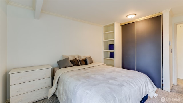 carpeted bedroom featuring beamed ceiling and a closet