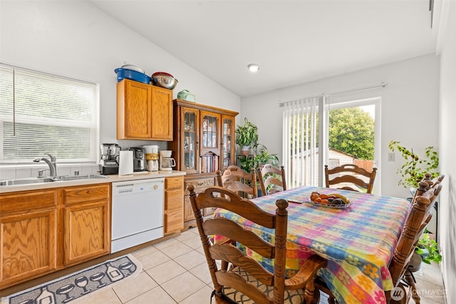 kitchen featuring white dishwasher, a sink, light countertops, light tile patterned floors, and lofted ceiling