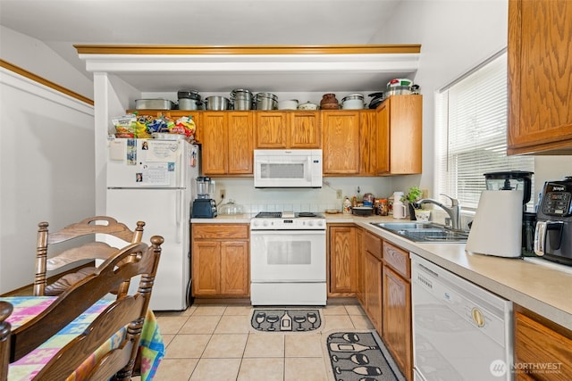 kitchen featuring white appliances, light tile patterned floors, a sink, and light countertops