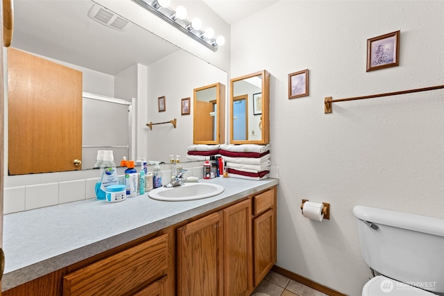 bathroom with tile patterned flooring, vanity, toilet, a shower with door, and visible vents