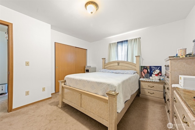 bedroom featuring light colored carpet, baseboards, and a closet