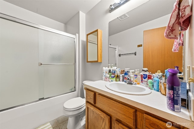 bathroom with vanity, toilet, tile patterned floors, combined bath / shower with glass door, and visible vents