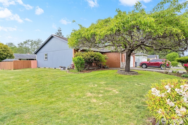 view of yard with a garage, aphalt driveway, and fence