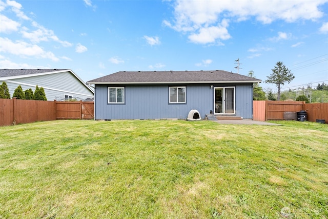 rear view of house featuring a fenced backyard and a lawn
