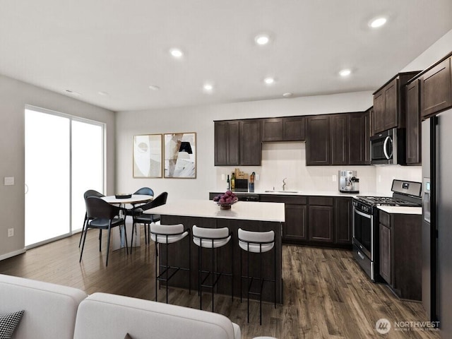 kitchen featuring a sink, stainless steel appliances, dark brown cabinetry, and dark wood finished floors