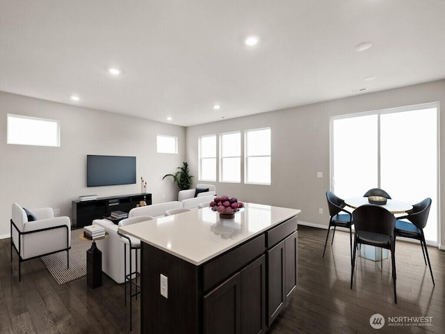 kitchen featuring dark wood-style floors, a breakfast bar area, a center island, and light countertops