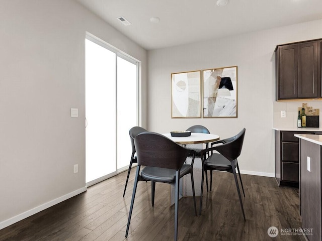 dining area with dark wood-style floors, visible vents, and baseboards