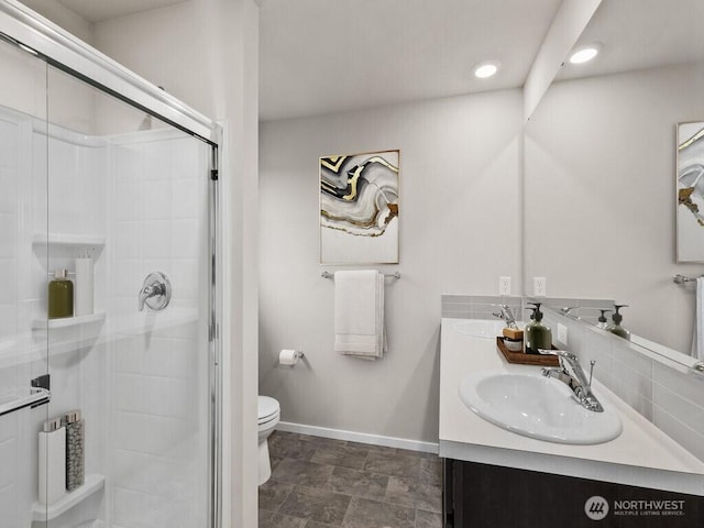 bathroom with toilet, a sink, a shower stall, double vanity, and baseboards