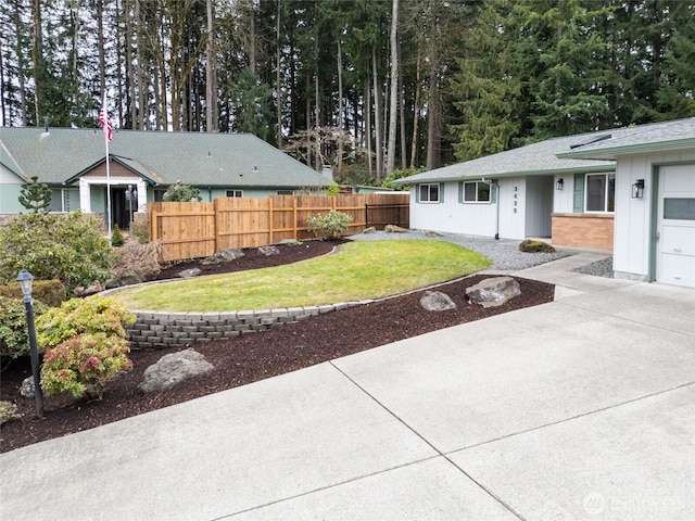 view of yard featuring a garage, driveway, and fence