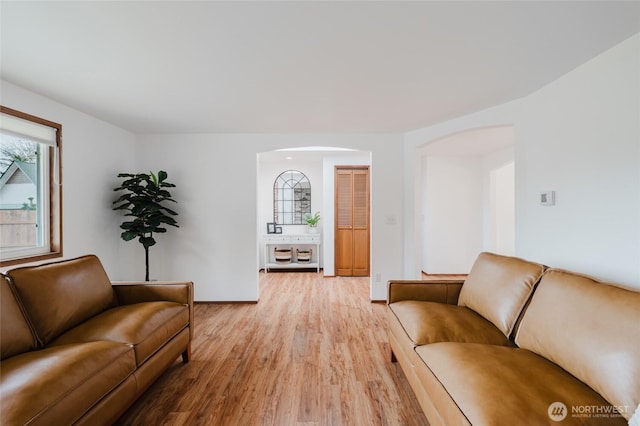 living room featuring arched walkways and light wood finished floors