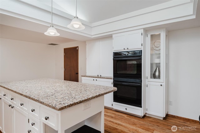 kitchen with light wood-style floors, a kitchen island, white cabinets, and dobule oven black