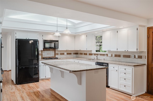 kitchen featuring a sink, a tray ceiling, black appliances, and white cabinetry