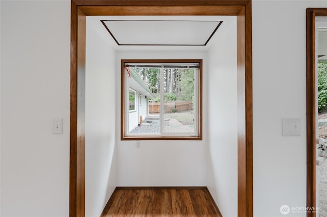 corridor featuring dark wood-type flooring and baseboards