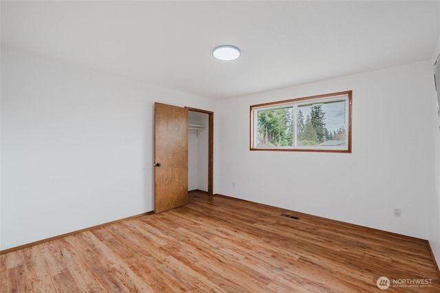 empty room featuring visible vents, baseboards, and wood finished floors