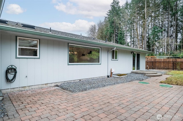 rear view of property with a patio area, fence, and roof with shingles