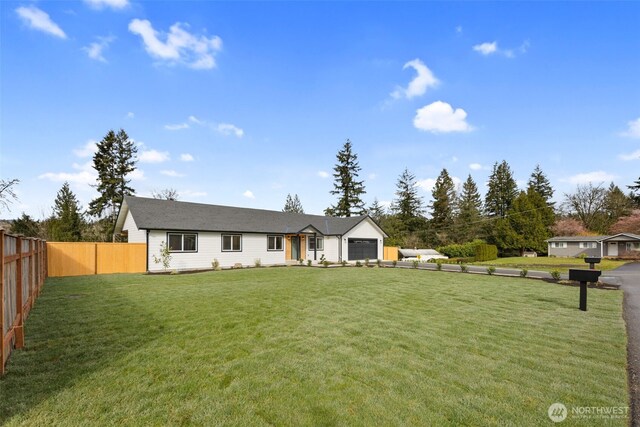 view of front of property with a front yard, an attached garage, and fence