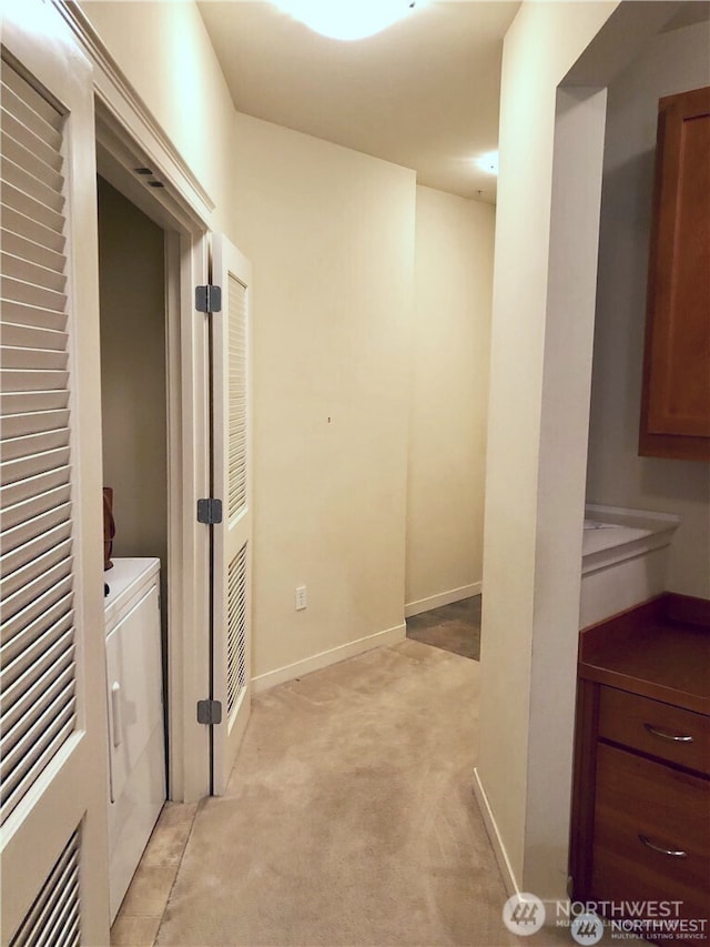 hall with washer and dryer, baseboards, and light carpet