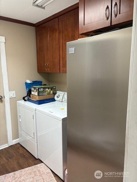 laundry area featuring baseboards, cabinet space, dark wood-type flooring, crown molding, and washer and clothes dryer