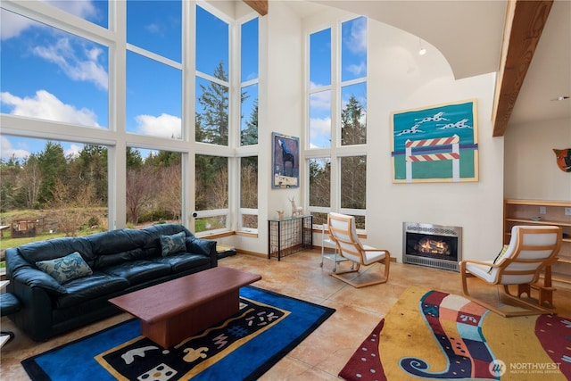 living room with tile patterned flooring, baseboards, a lit fireplace, a high ceiling, and heating unit