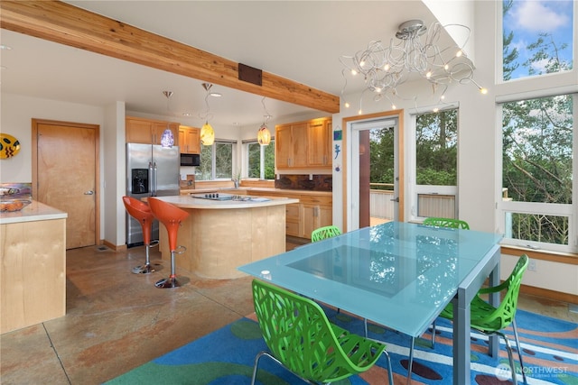 kitchen with beam ceiling, a center island, stainless steel fridge, black microwave, and light countertops