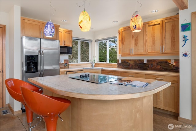 kitchen with visible vents, black appliances, a sink, a kitchen island, and decorative backsplash