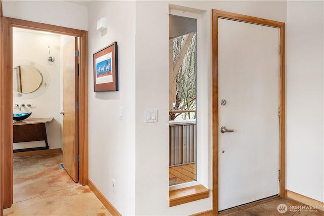 foyer entrance with baseboards and concrete flooring