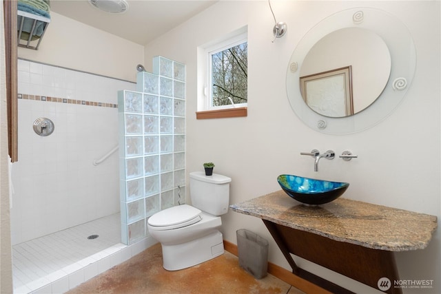 bathroom with toilet, walk in shower, baseboards, and a sink