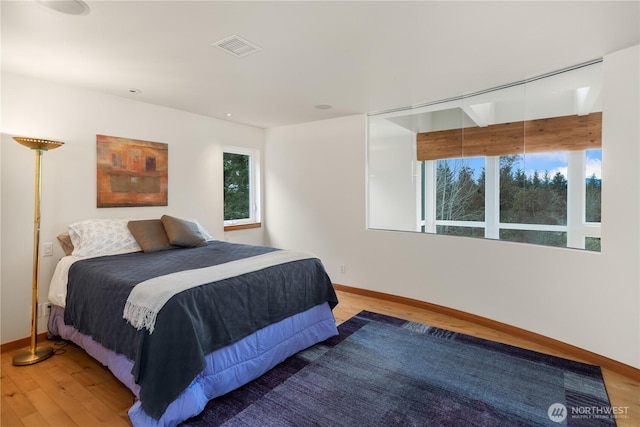 bedroom with visible vents, baseboards, and wood finished floors