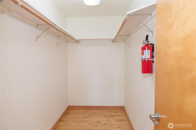 walk in closet with light wood-style floors