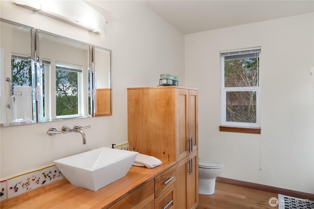 bathroom with a wealth of natural light, visible vents, toilet, and wood finished floors